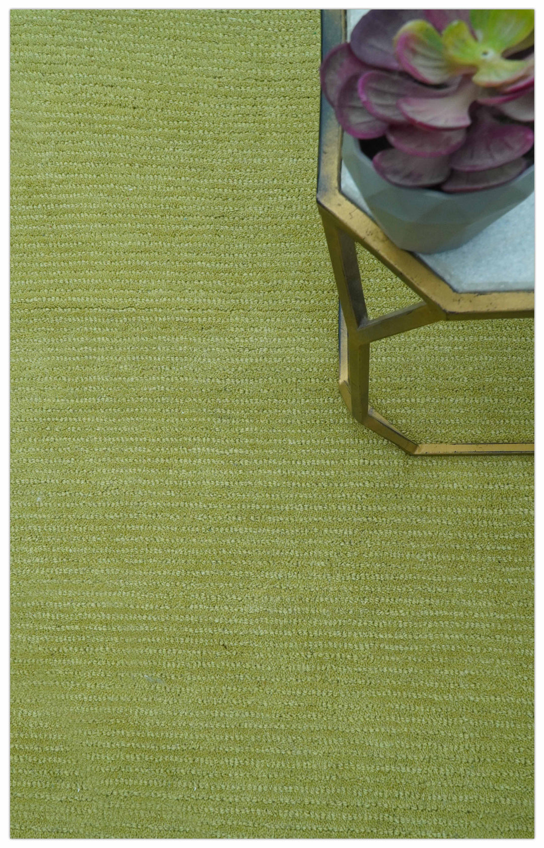 Green wool rug shown beneath a small table, revealing its textured surface
