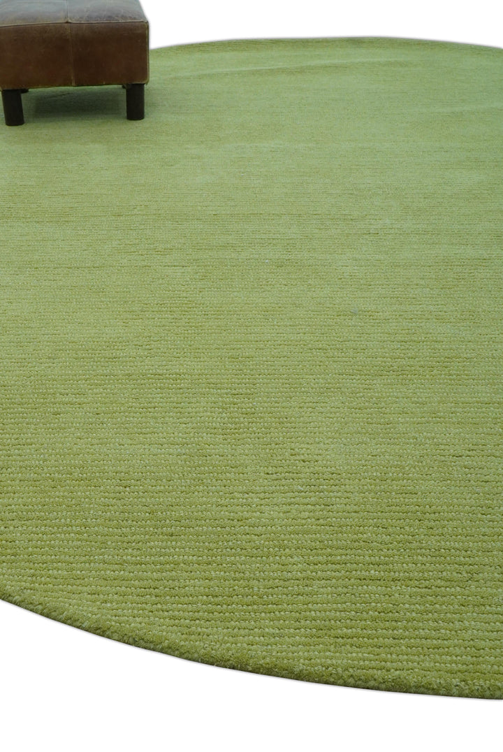 Green round wool rug shown in a room with a chair at the edge