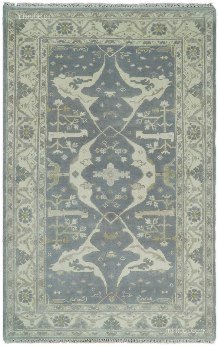 Rectangular traditional patterned rug in blue-gray and ivory, ornate border and central motif.