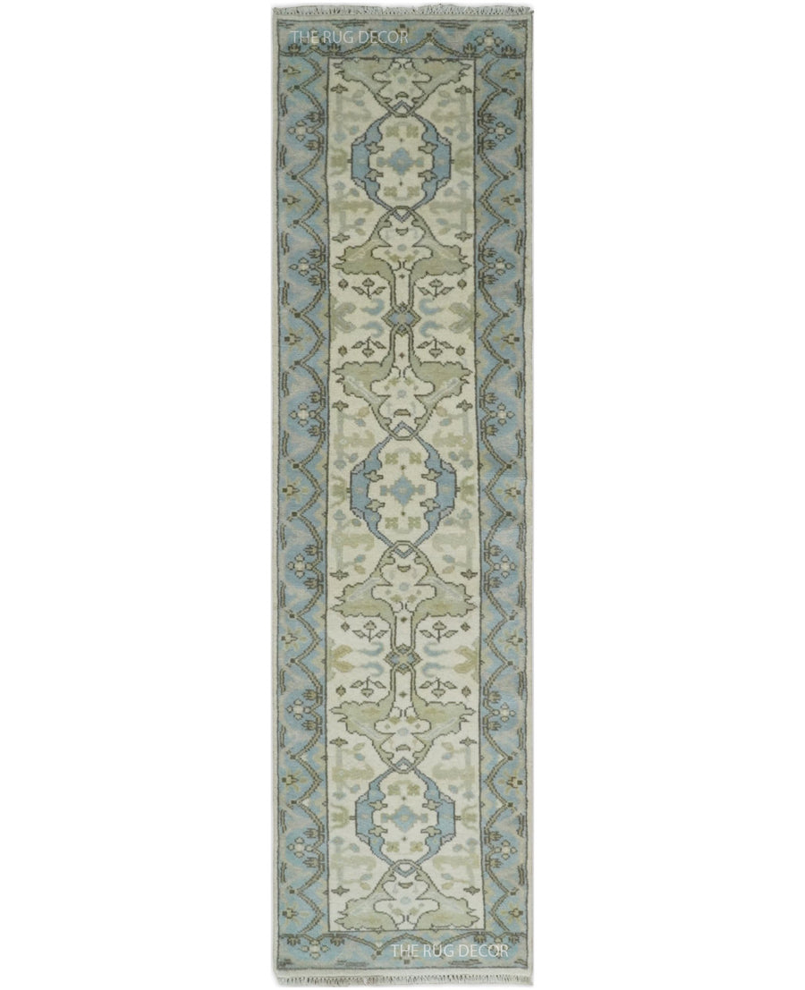 Ivory and blue hand-knotted wool runner rug with a central floral motif and patterned border