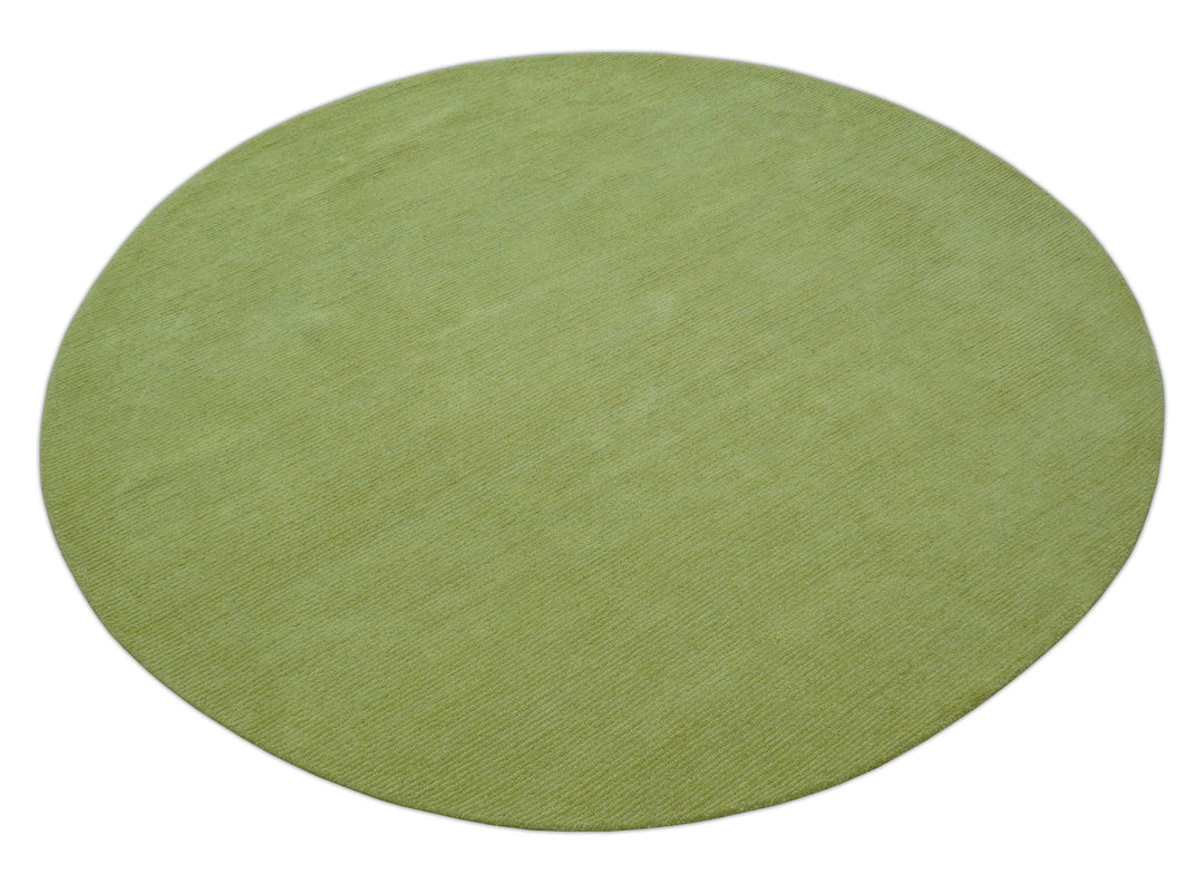 Green round wool rug shown at an angle, with a subtly textured solid surface