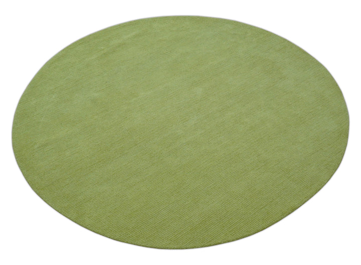 Green round wool rug shown at an angle, with a subtly textured solid surface