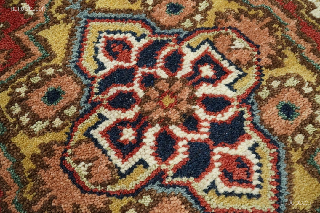 Close-up of the wool runner rug's raised floral medallion in rust, blue, cream, and gold