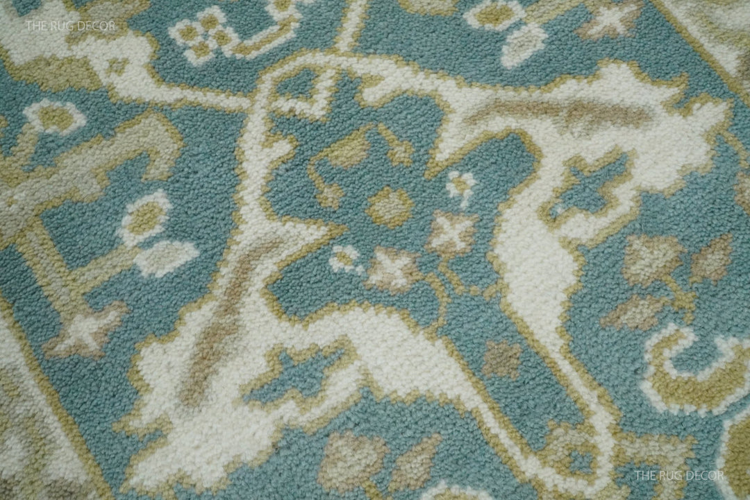Close-up of the rug's teal, ivory, and muted gold floral pile