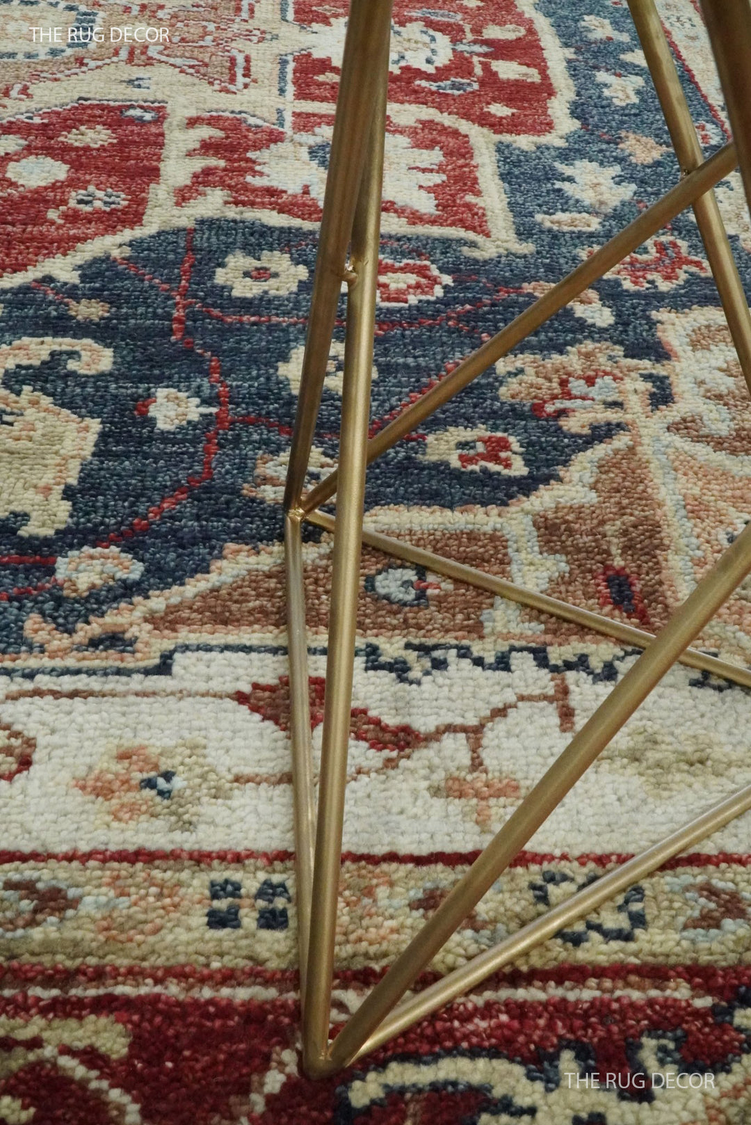 Hand-knotted wool rug detail showing the dense pile and red, blue, and cream motifs