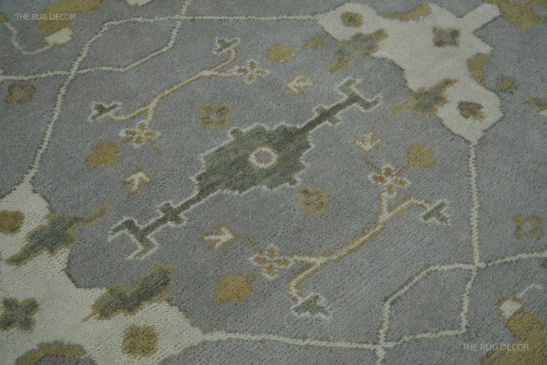 Close-up of gray wool rug pile with ivory, olive, and gold geometric floral motifs