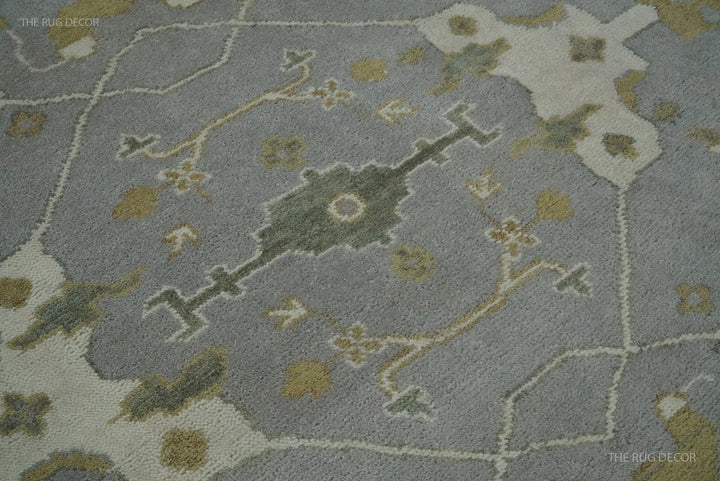 Close-up of gray wool rug pile with ivory, olive, and gold geometric floral motifs