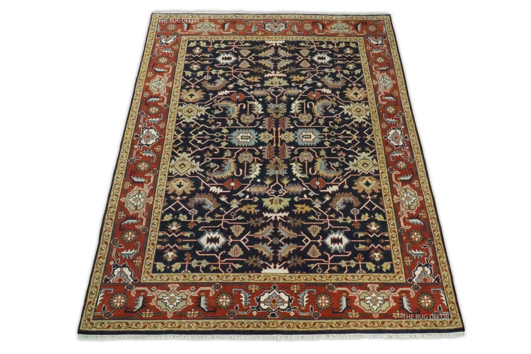 Full view of a traditional rug with a navy center and red patterned border