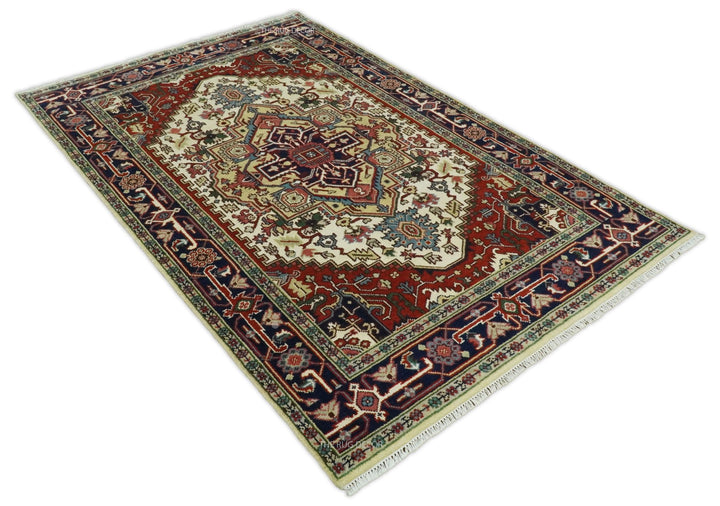 Traditional hand-knotted wool rug, angled view, ivory field with maroon and navy geometric pattern