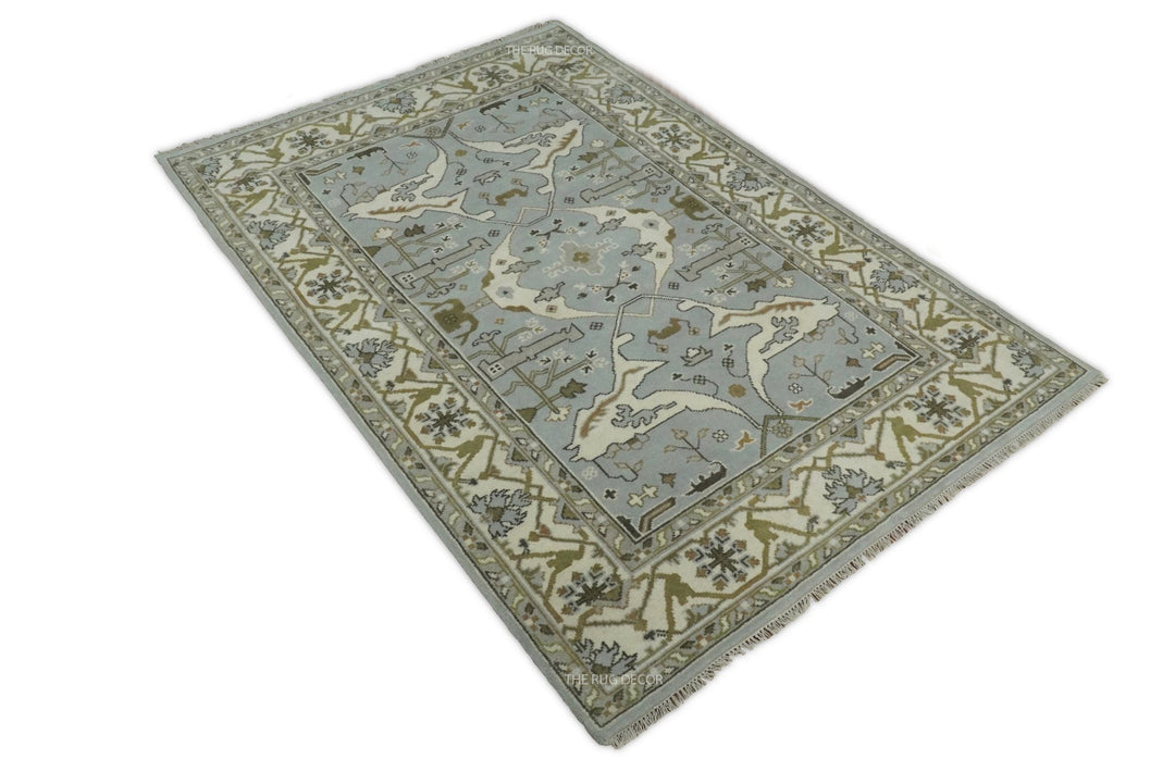 Oushak rug in bluish silver and ivory, shown at an angle with an ornate floral pattern