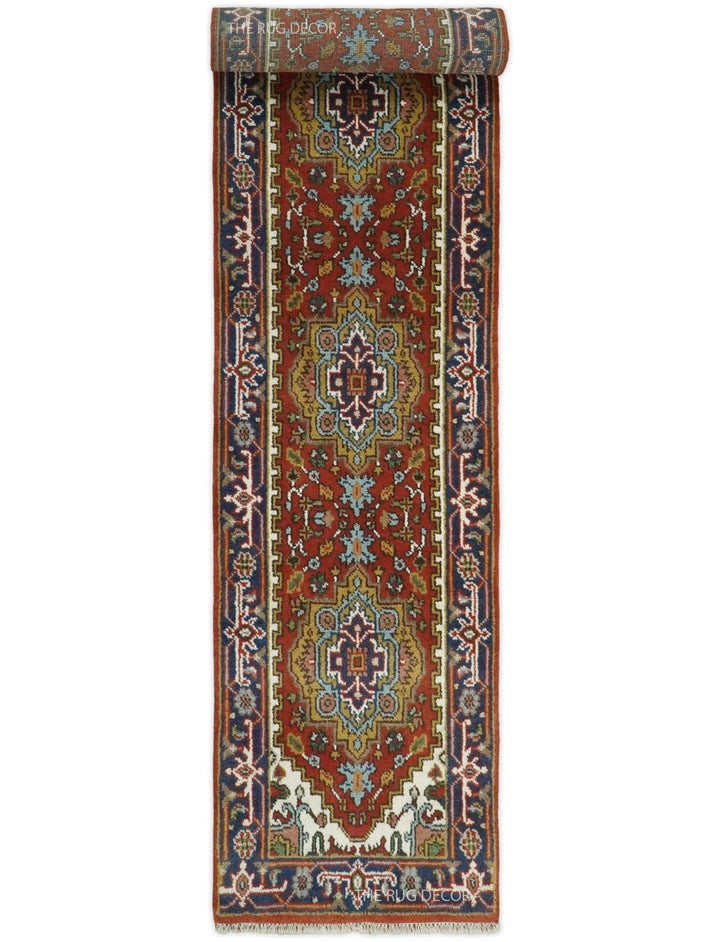 Rust and blue wool runner rug rolled at one end, showing its floral pattern