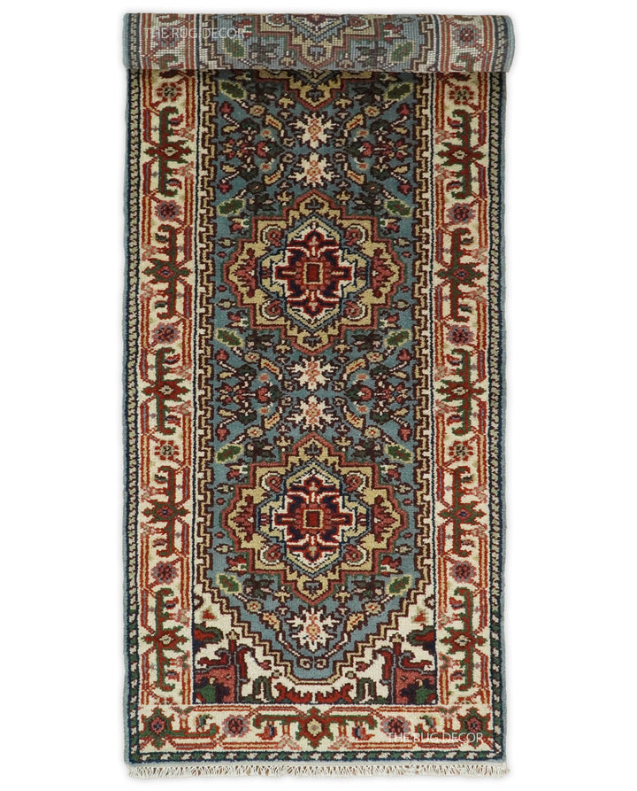 Blue and ivory wool runner rug shown partially rolled, with traditional medallions