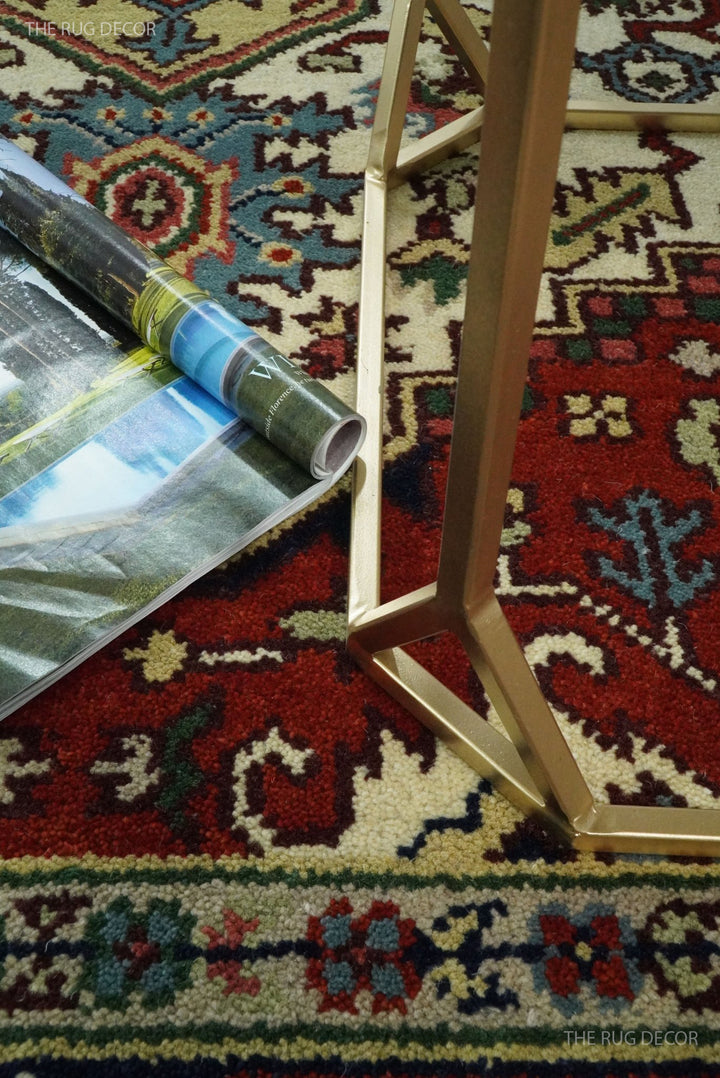 Hand-knotted wool rug corner detail with fringe, ivory motifs and maroon-red base