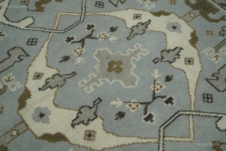 Close-up of bluish silver wool rug pile with ivory motifs and small floral details