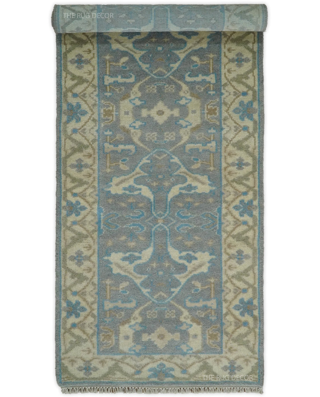 Gray and beige runner rug rolled at one end, displaying its blue floral design and fringe
