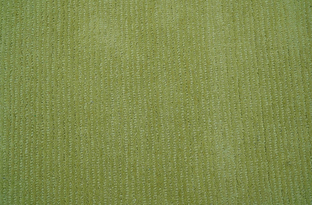 Close-up of the rug's green wool pile and tufted texture