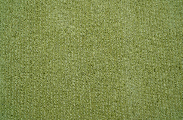 Close-up of the rug's green wool pile and tufted texture