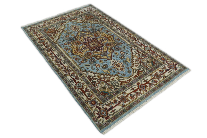 Sera hand-knotted rug shown at an angle, with an ornate blue and ivory design
