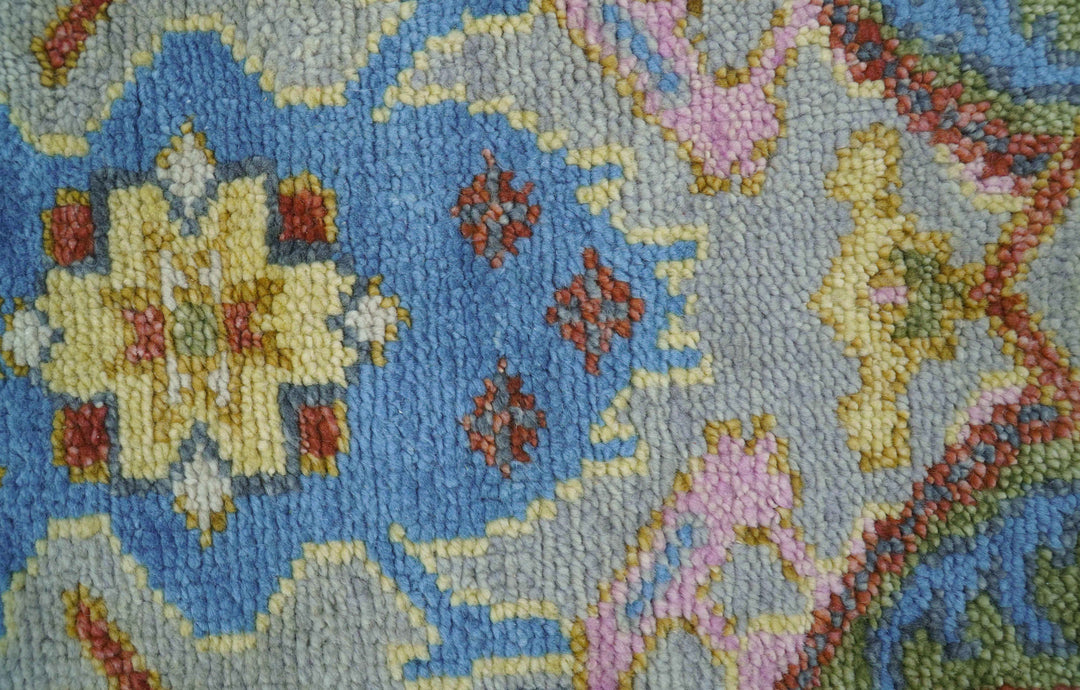 Close-up of multicolor tufted wool rug pile with blue, pink, and green motifs