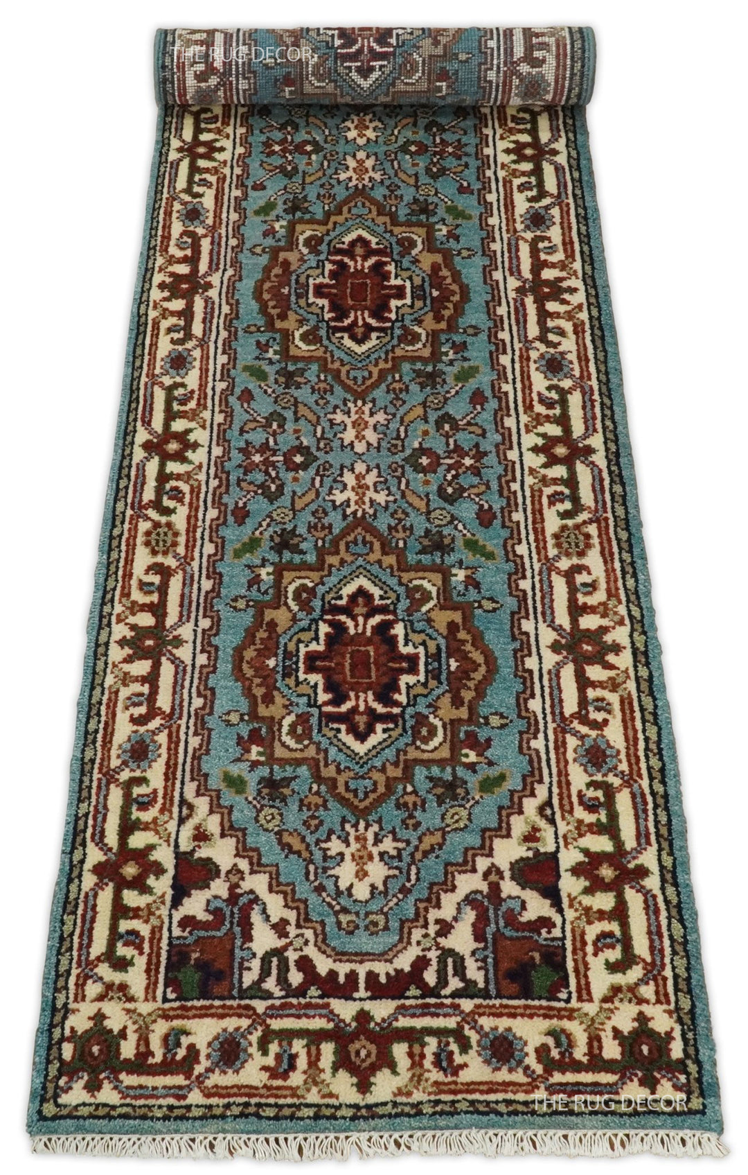Blue and ivory runner rug partially unrolled, with floral medallions and fringe