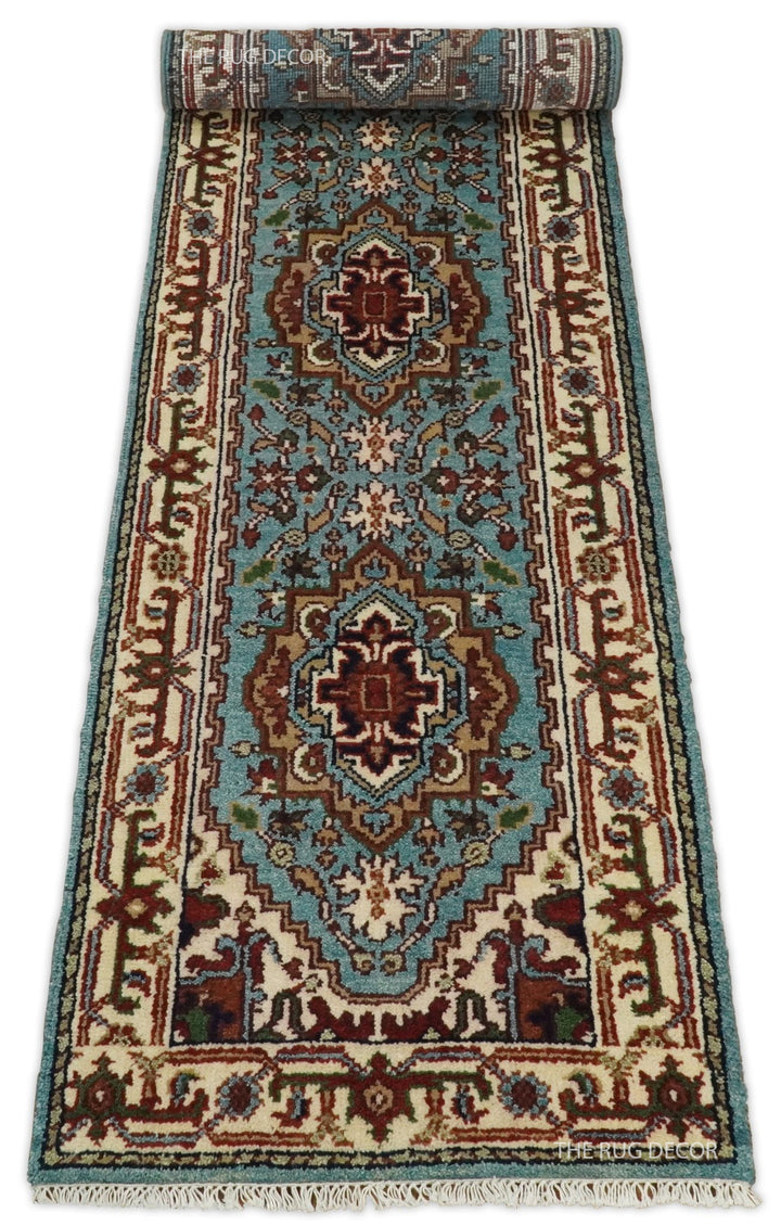Blue and ivory runner rug partially unrolled, with floral medallions and fringe