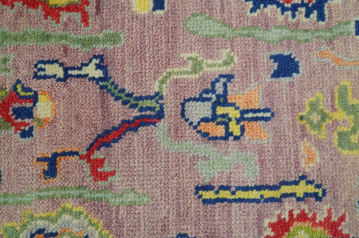 Close-up of Traditional Oushak wool rug texture with multicolor motif on pastel pink