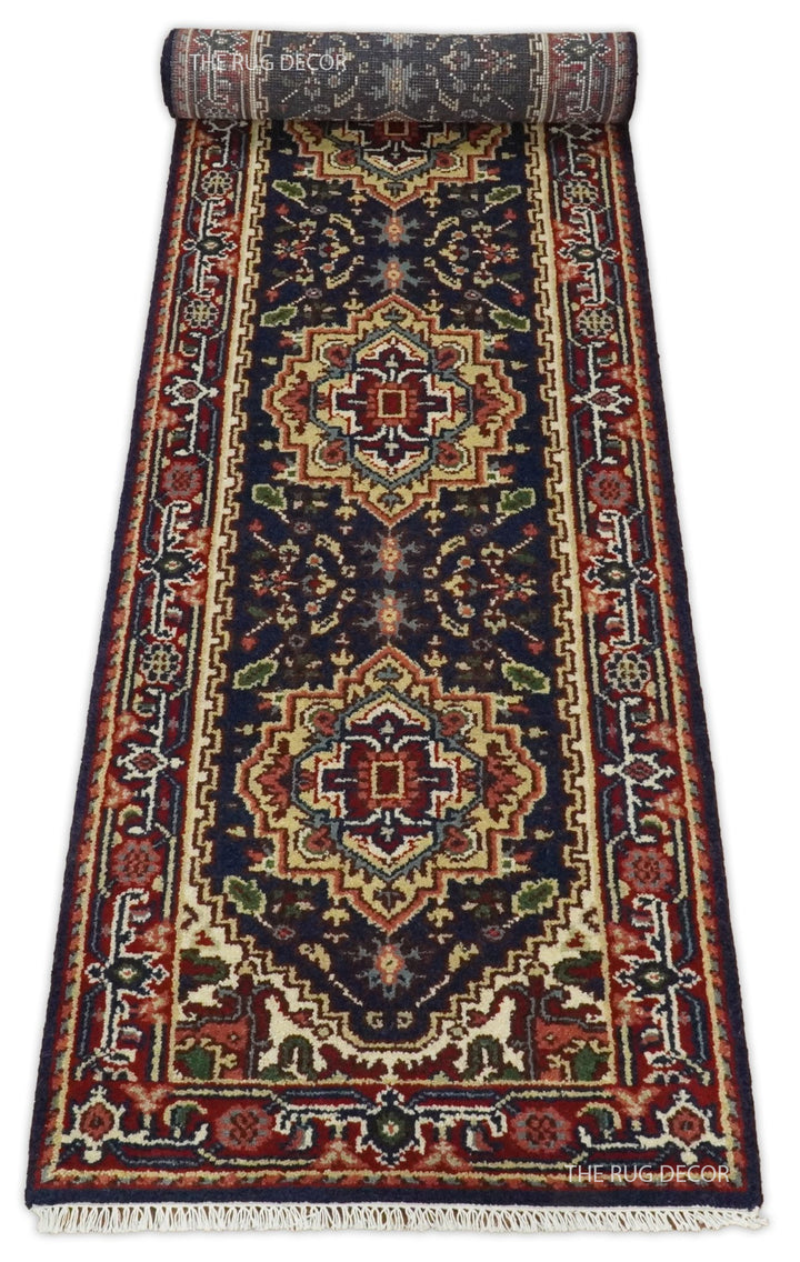 Partially rolled red and dark blue wool runner with geometric medallions and fringe