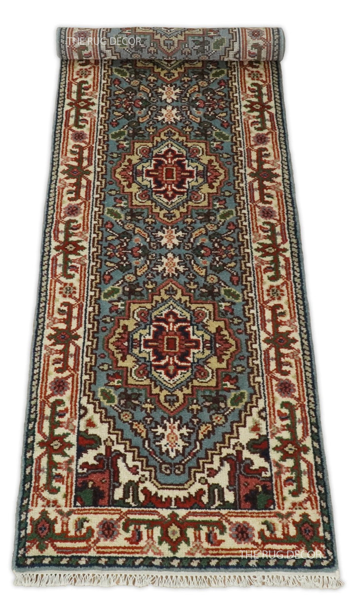 Traditional wool runner rug with blue center, ivory borders, and fringe