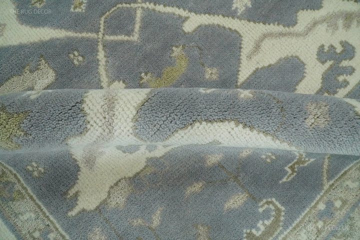 Close-up of blue-gray rug surface with ivory cloud-like motif and small border lines.