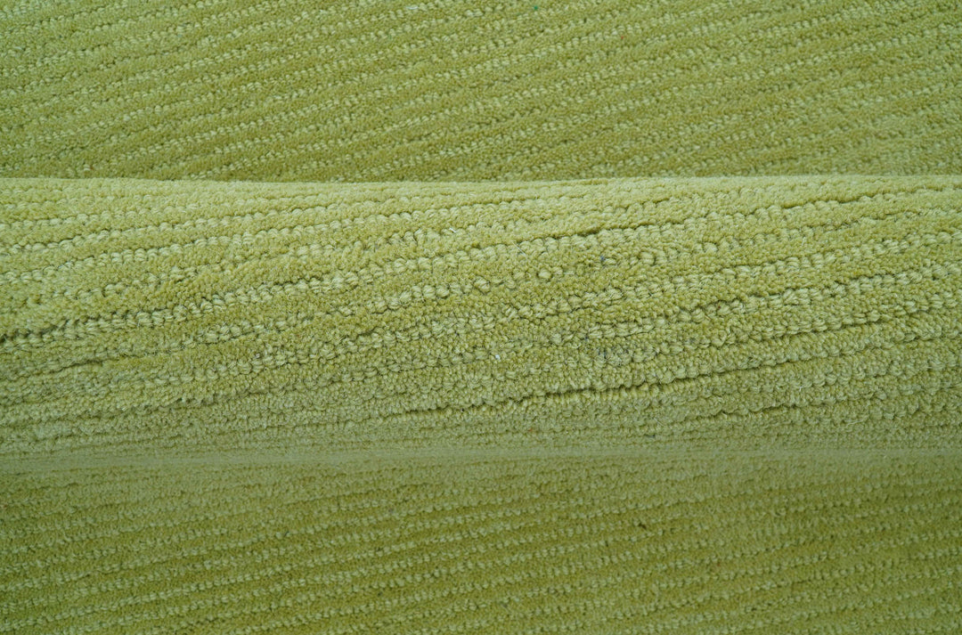 Close-up of the green wool rug's thick tufted pile and edge