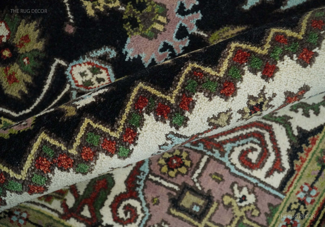 Hand-knotted wool rug close-up showing floral and vine motifs in cream, red, and green