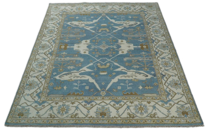Blue and ivory Oushak wool rug shown from the front, with a central medallion and floral border