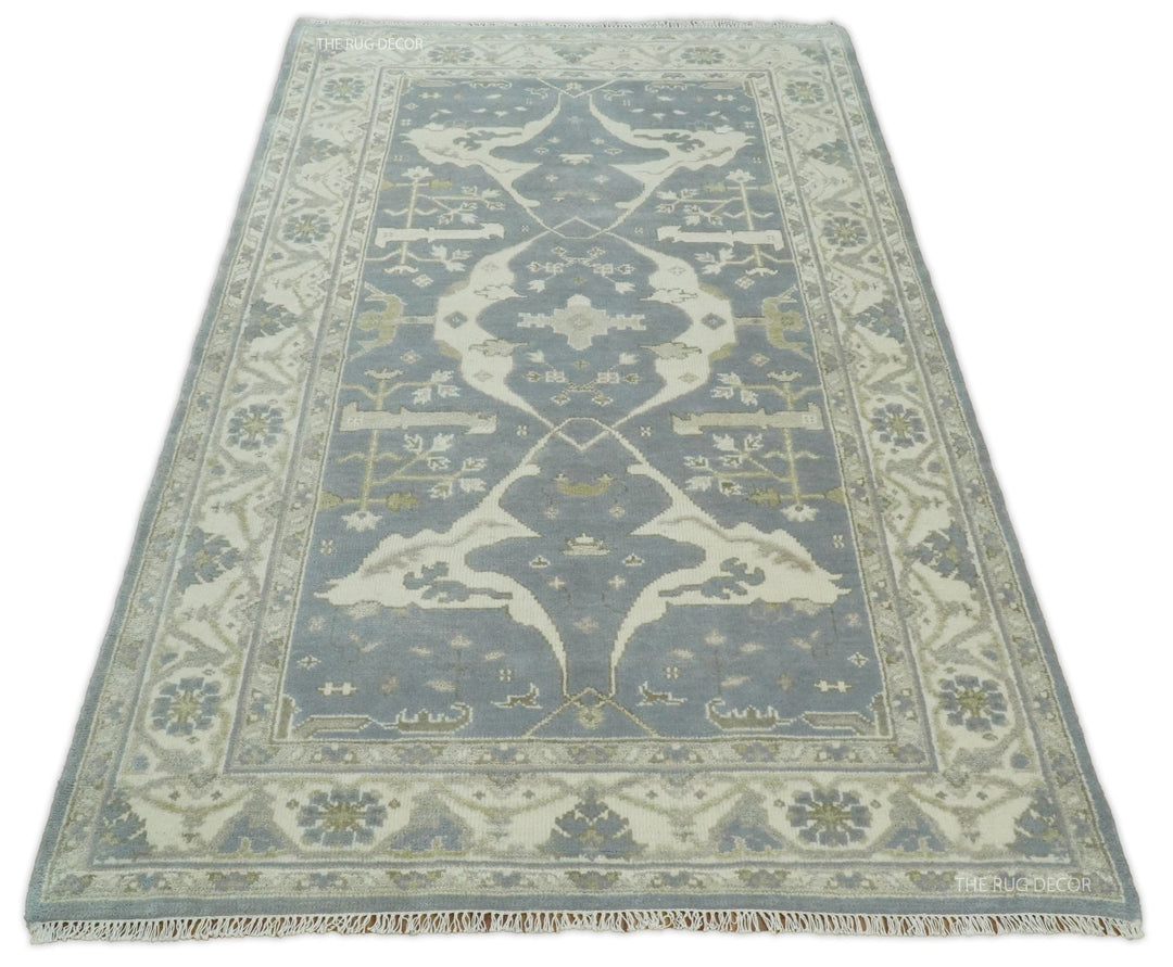 Traditional area rug in blue-gray and ivory with symmetrical vines and geometric border.
