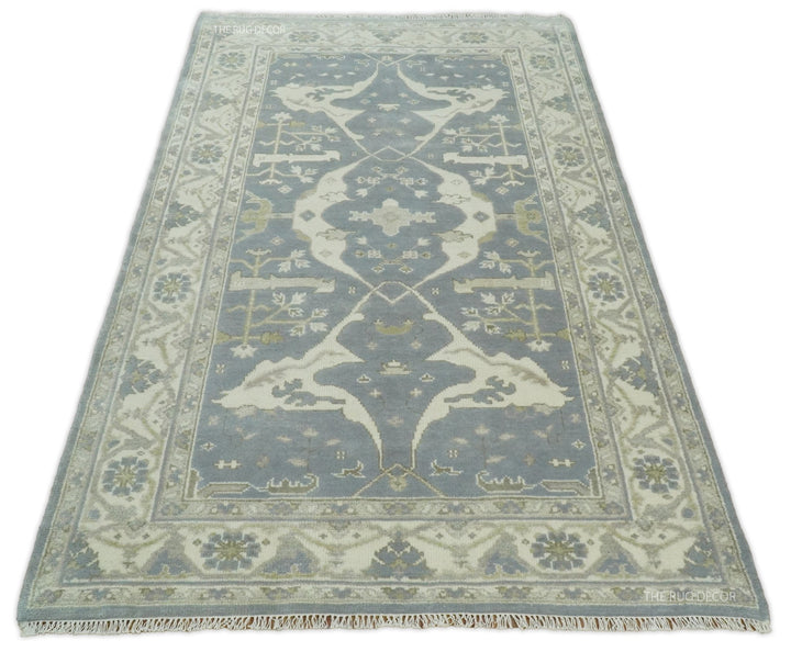Traditional area rug in blue-gray and ivory with symmetrical vines and geometric border.