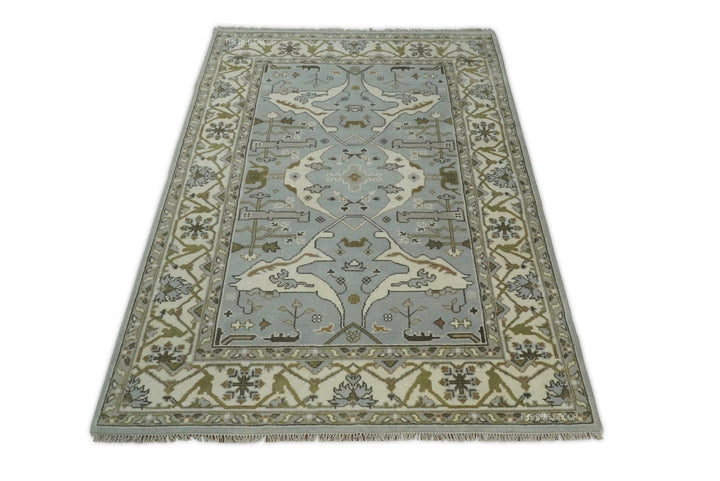 Bluish silver and ivory Oushak rug with central medallion and patterned border, viewed from the end