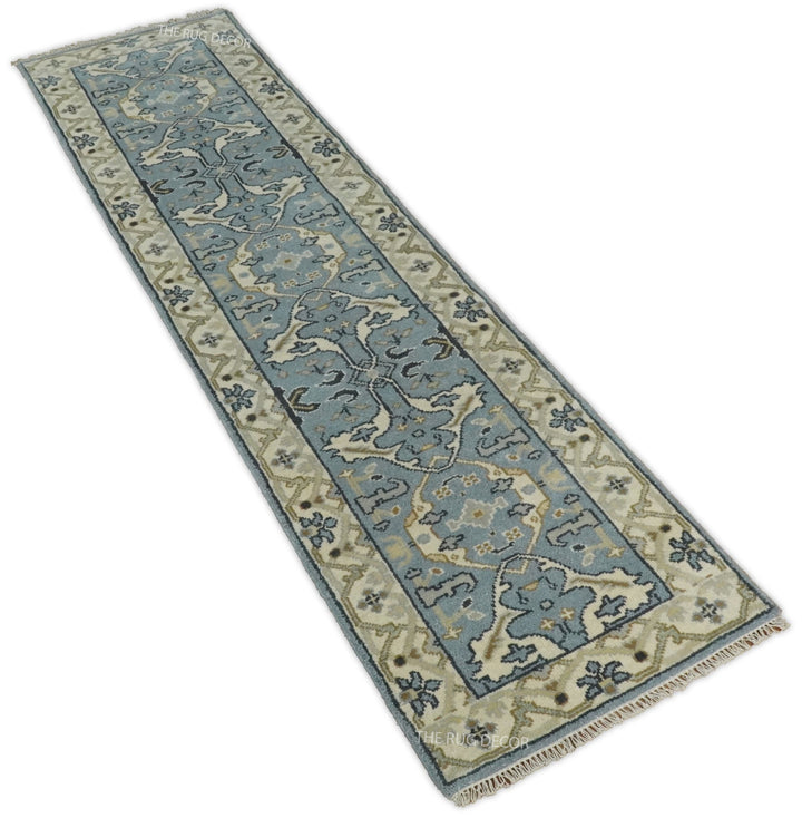Hand-knotted wool runner rug shown diagonally, with a blue-gray center and beige border