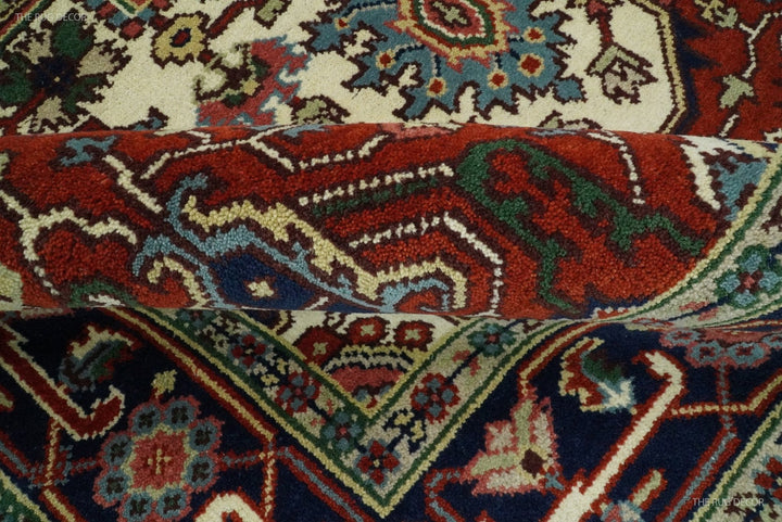Close-up of hand-knotted wool rug pattern with maroon, navy, teal, and ivory highlights