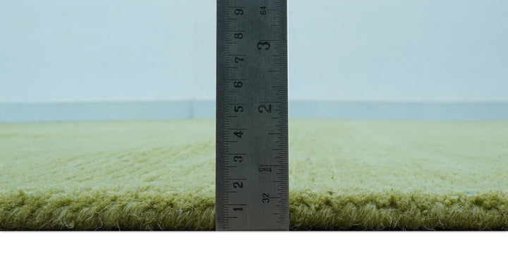 Side view of the rug's thick green wool pile beside a ruler