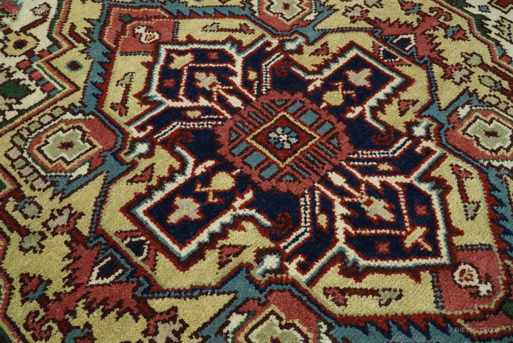 Hand-knotted wool rug close-up with central dark-blue medallion on ivory and maroon ground