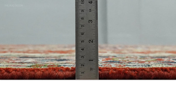 Red hand-knotted rug side profile beside a ruler, showing its pile thickness