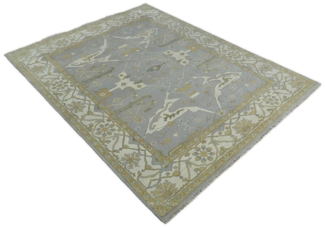 Angled view of gray and ivory Oushak rug with central medallion and ornate border