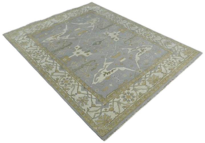 Angled view of gray and ivory Oushak rug with central medallion and ornate border