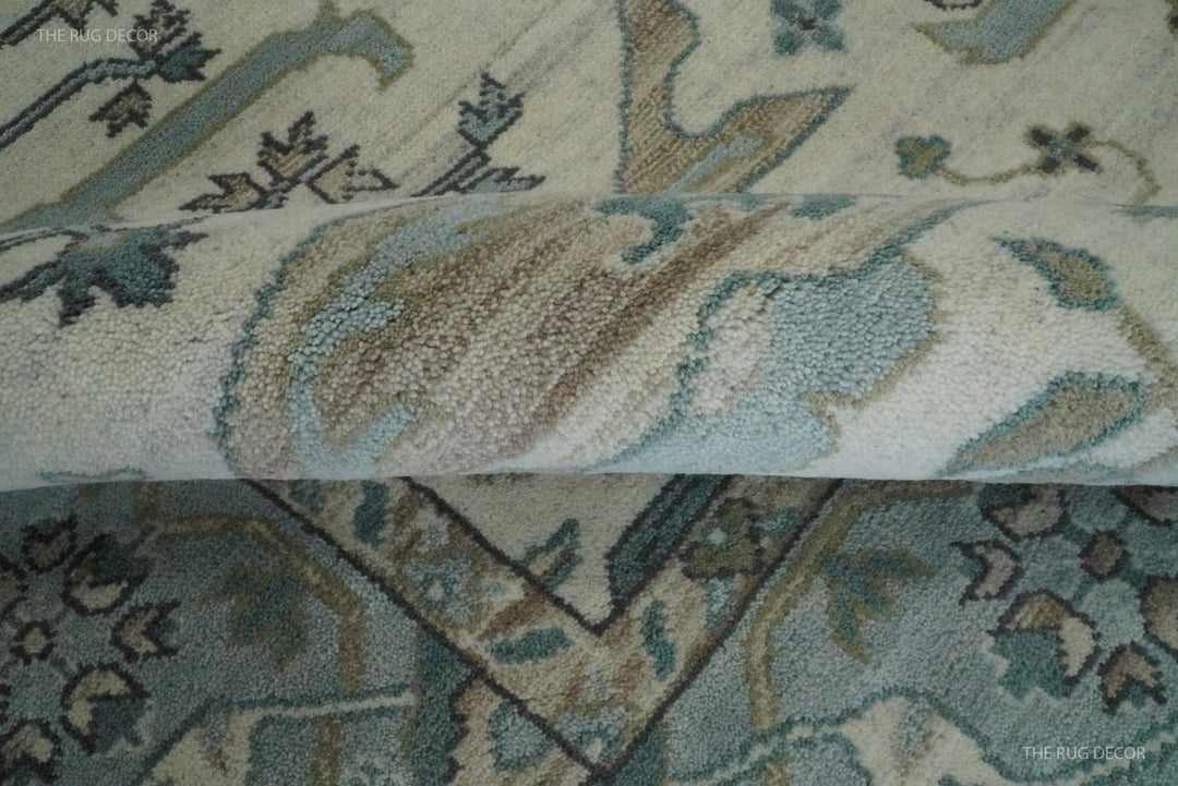 Folded edge reveals the thick wool pile and woven pattern of the Oushak rug