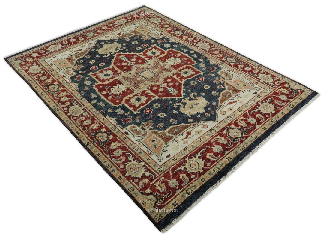 Angled view of a traditional red and blue Serapi rug with an ornate border