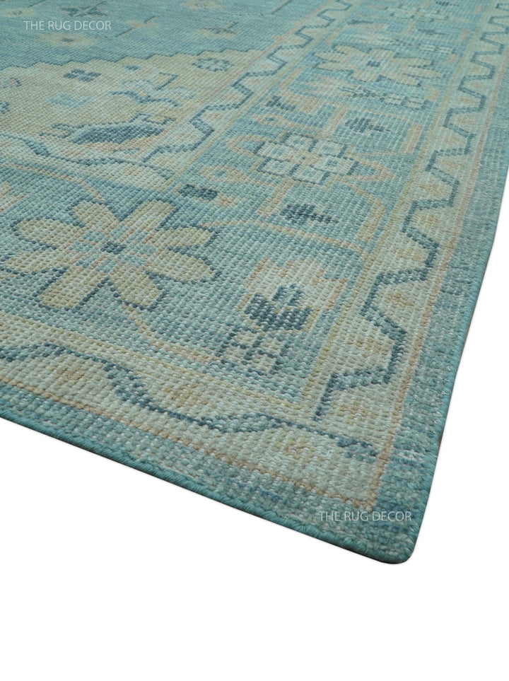 Hand-knotted wool area rug corner detail with blue tone, beige highlights, and border