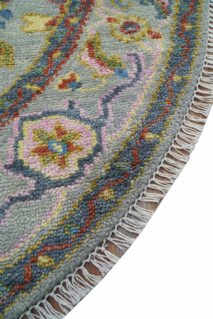 Diagonal view of multicolor round wool rug with decorative border and fringe trim