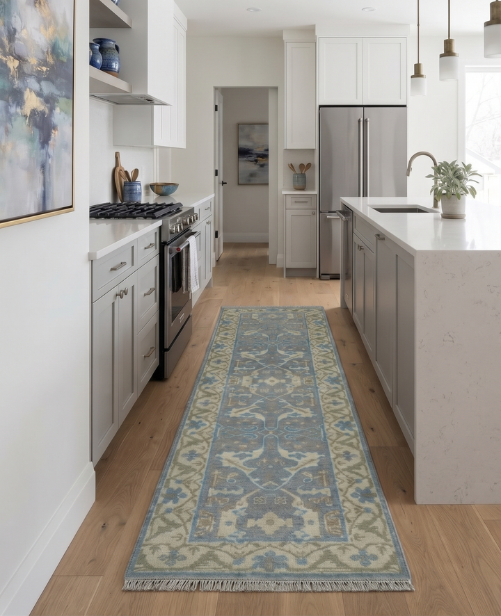 Gray and beige Oushak wool runner with blue motifs and fringed ends, shown on a kitchen floor