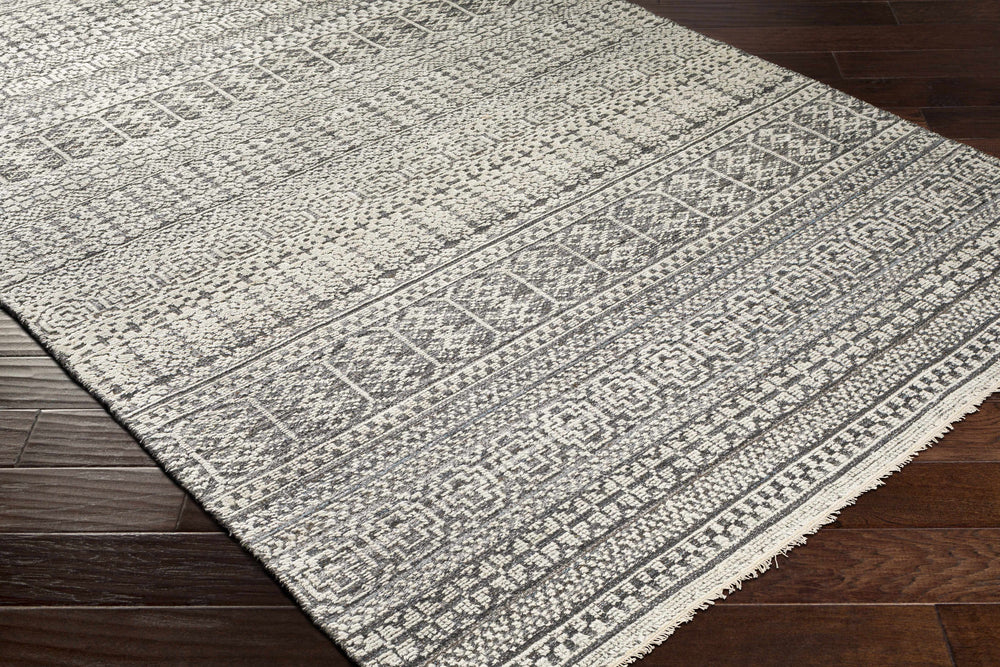 Ivory and charcoal geometric area rug, corner detail with woven border