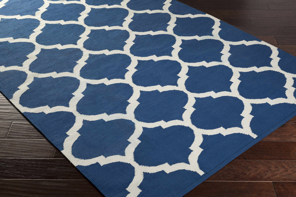 Blue geometric area rug with white quatrefoil pattern, corner view
