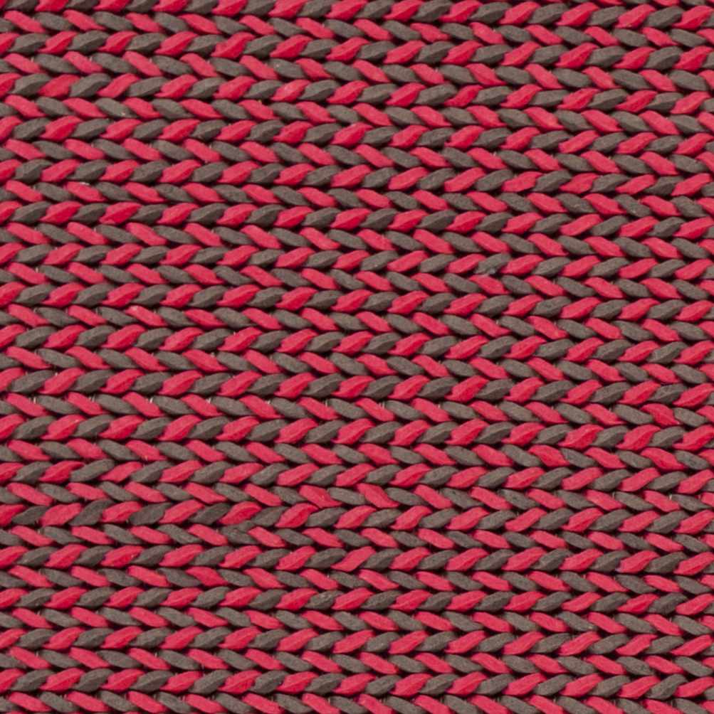 Hand-woven red and dark area rug close-up, braided crisscross weave texture